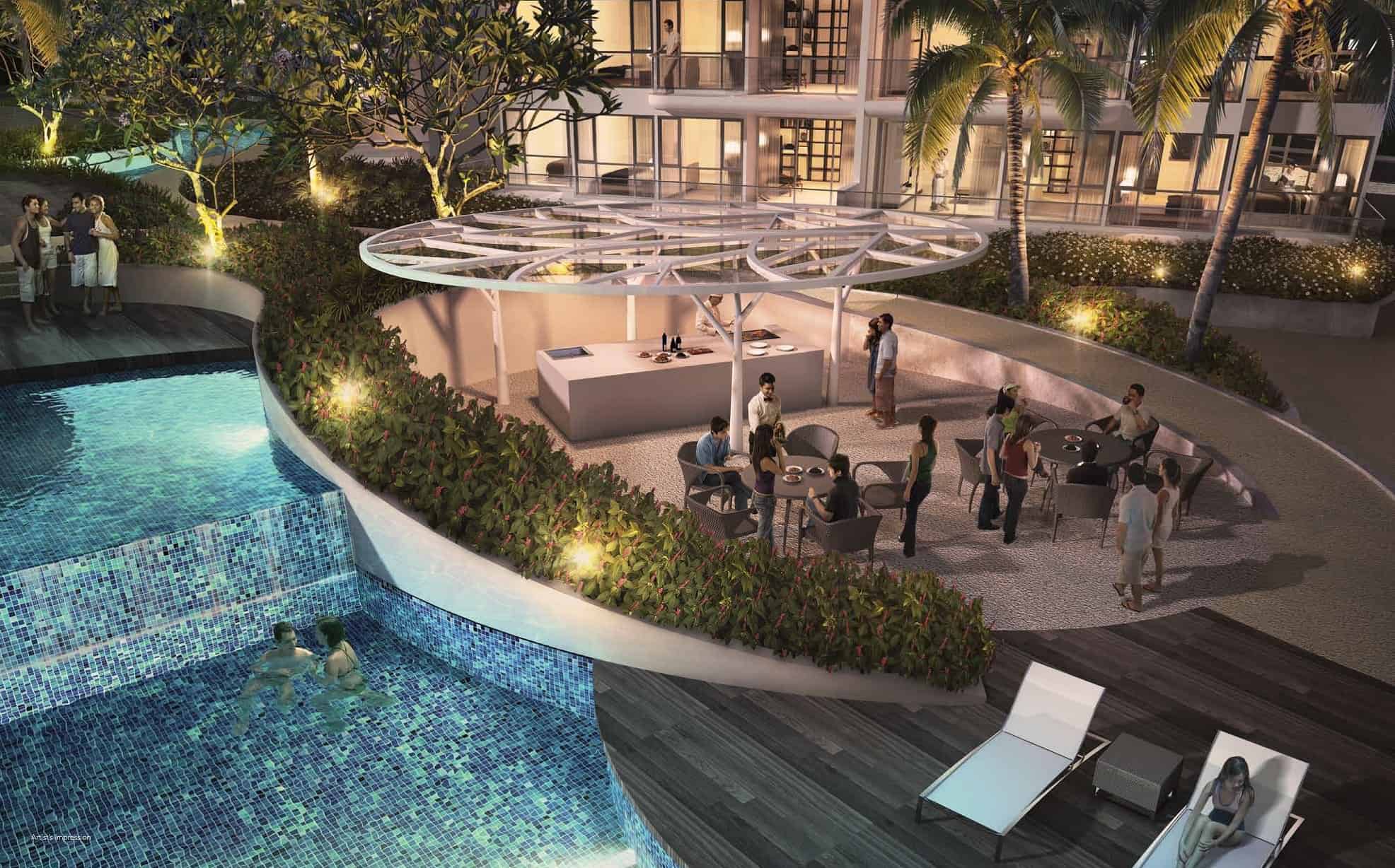 Evening scene at Riversound Residence showing residents socializing at an outdoor dining pavilion next to a cascading pool. Surrounded by tropical landscaping and soft ambient lighting, the area features a modern canopy structure with a central kitchen island, creating a warm, inviting atmosphere for gatherings and relaxation.